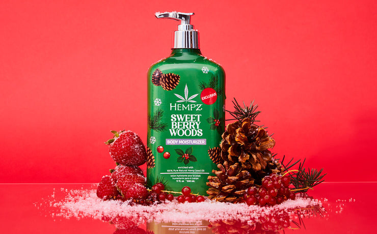 Hempz Sweet Berry Woods lotion bottle with berries and pinecones on a red background