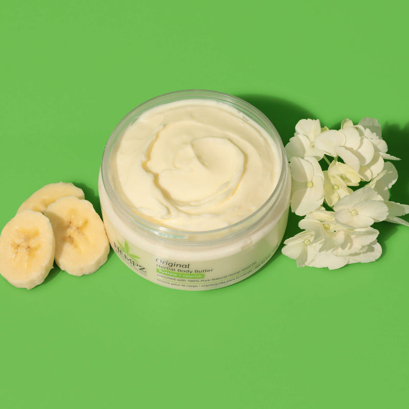 Bananas and white flowers and an open container of Hempz Original Body Butter to show texture